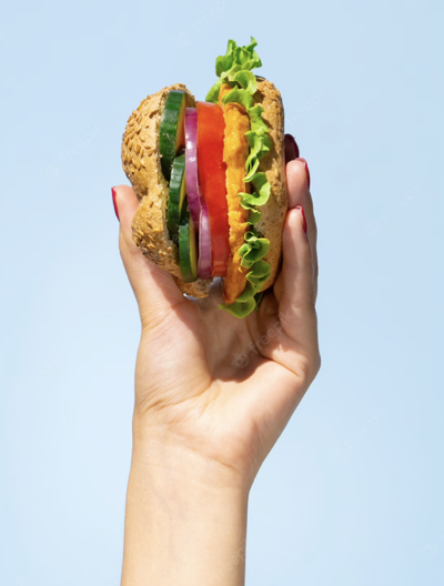 Sanduíche vegetariano segurado por uma mão feminina.