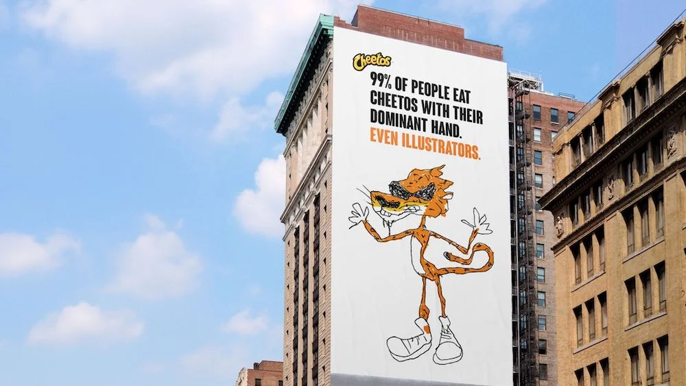 Cheetos billboard advertisement with cartoon mascot on a city building stating 99% of people eat with their dominant hand.