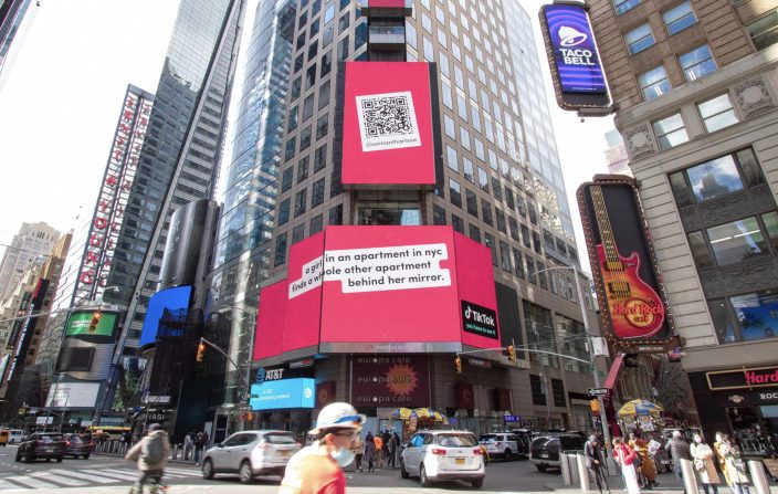 Billboard with QR code in Times Square promoting a TikTok story about a New York City apartment with a hidden room behind a mirror.