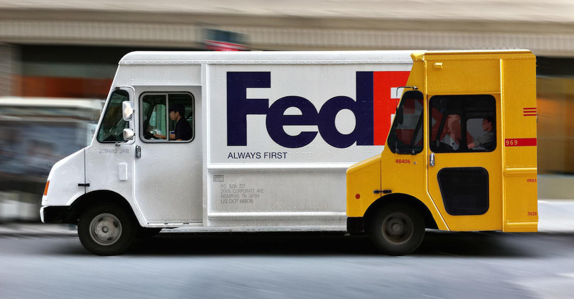 FedEx delivery truck in motion on city street with clear company branding and driver visible