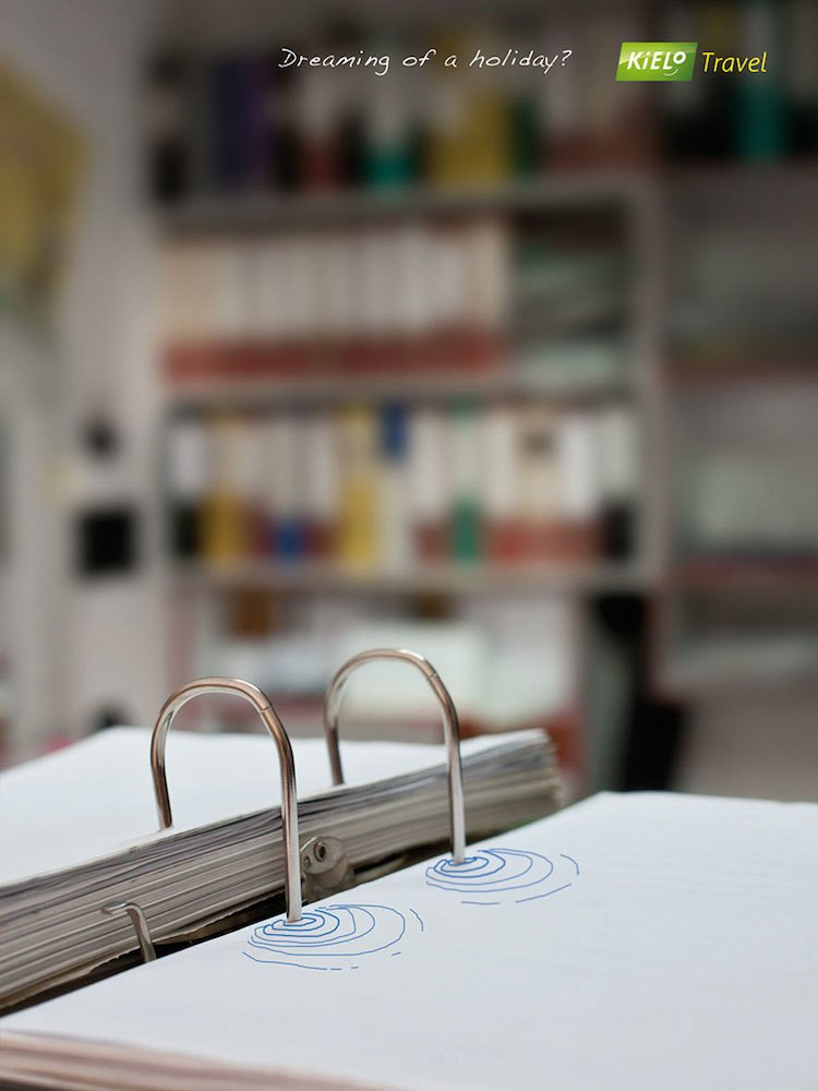 Open binder with doodles of water ripples on desk, travel agency advertisement in the background