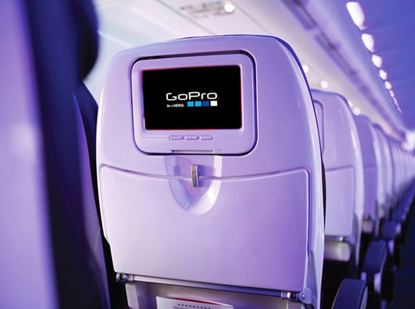 Airplane cabin interior with GoPro advertisement on seat-back entertainment screen