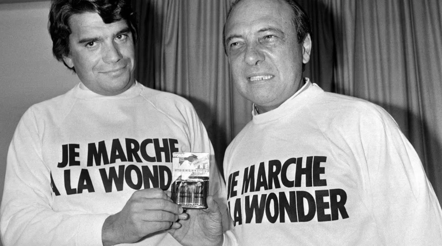 Jacques Séguéla. Two men wearing "Je Marche A La Wonder" shirts, one holding a pack of Wonder batteries.