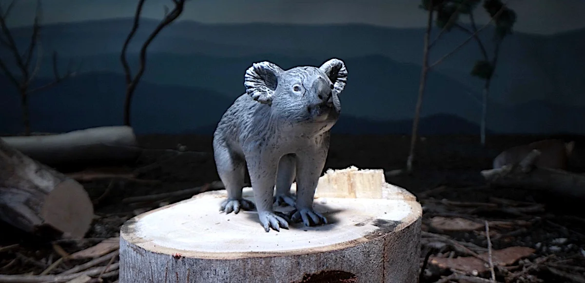 Koala model posed on tree stump in a simulated natural habitat display