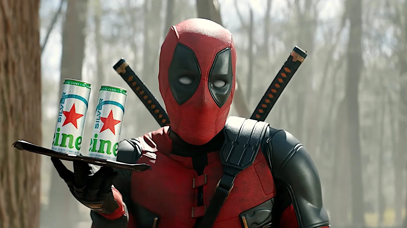 Deadpool holding a tray with two cans of Silver Line energy drink in a forest setting.