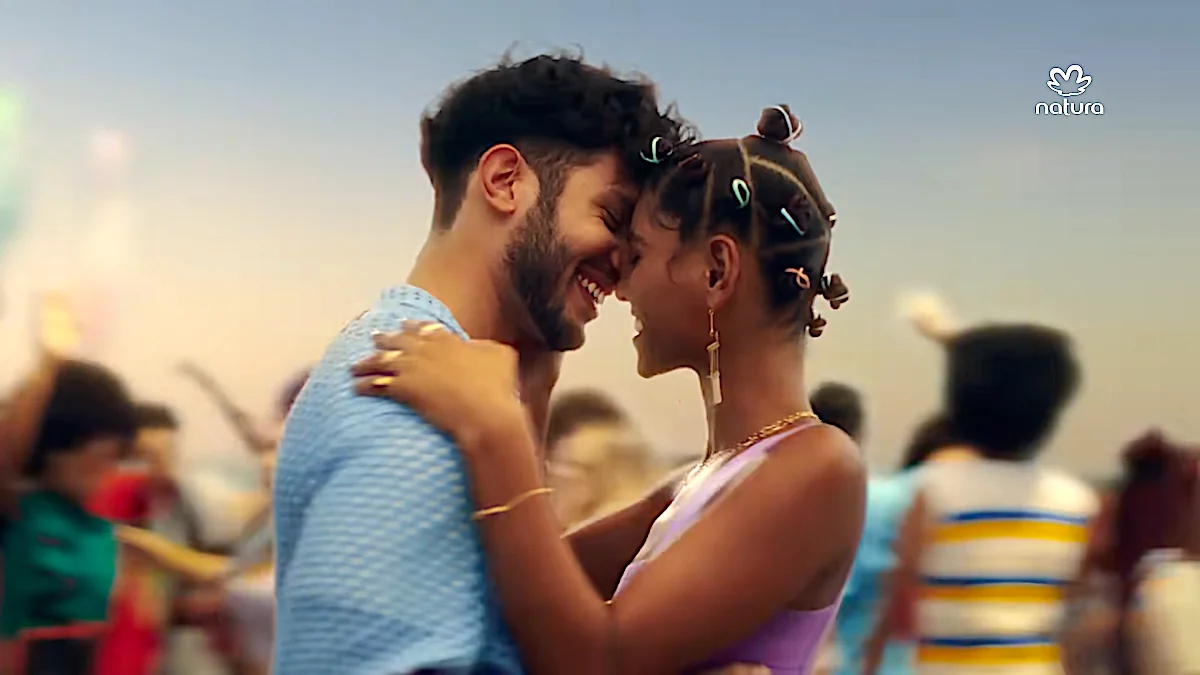 Happy couple embracing and smiling at an outdoor event, promoting Natura products.