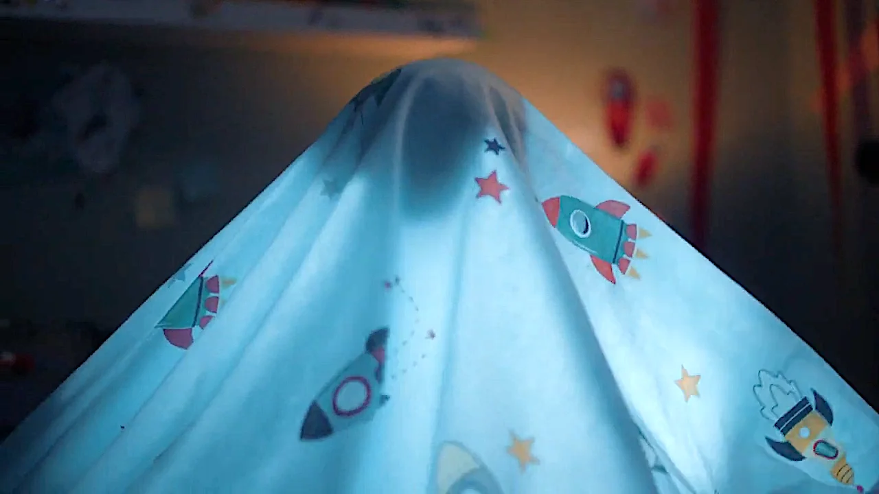 Space-themed blanket over child's fort with playfully illustrated rockets and stars.