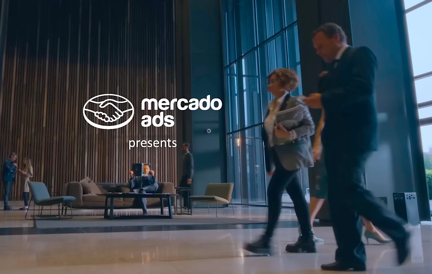 Mercado Ads presentation in a modern office lobby with people walking and sitting. FOMA