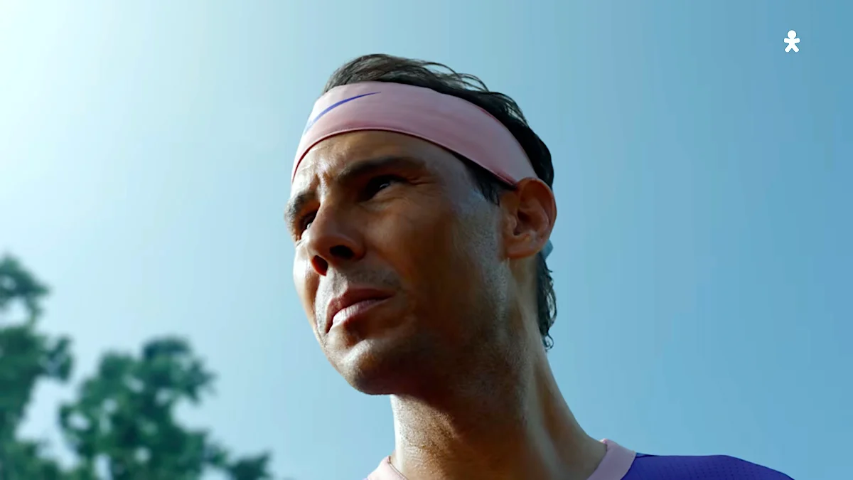 Male athlete wearing a pink headband looking determined against a clear blue sky.