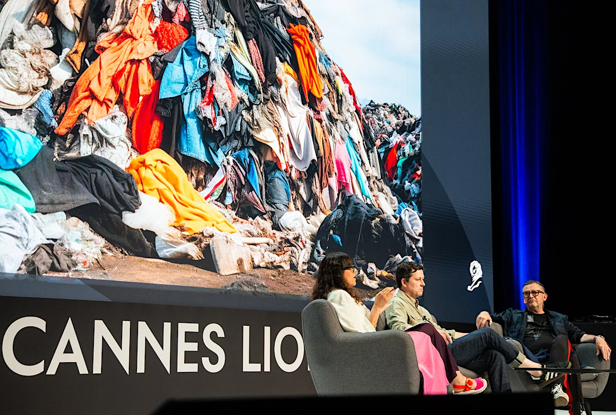 Panel discussion at Cannes Lions with a large screen displaying a pile of discarded clothing, highlighting fashion industry waste.