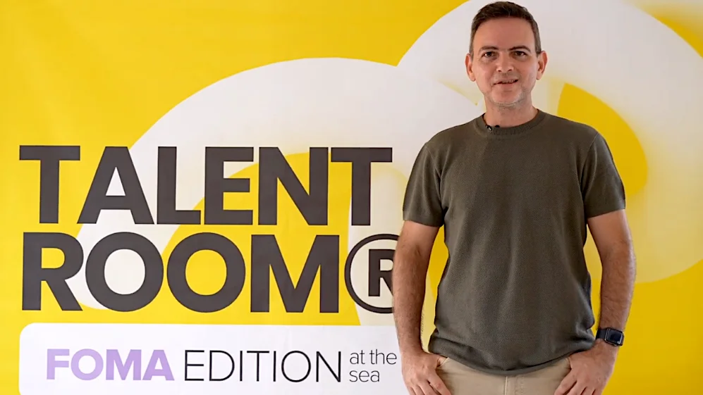 Man standing in front of Talent Room FOMA Edition at the Sea banner.