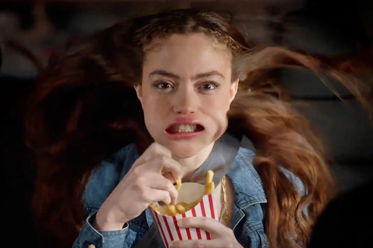 Woman eating fries with wind blowing her hair back.