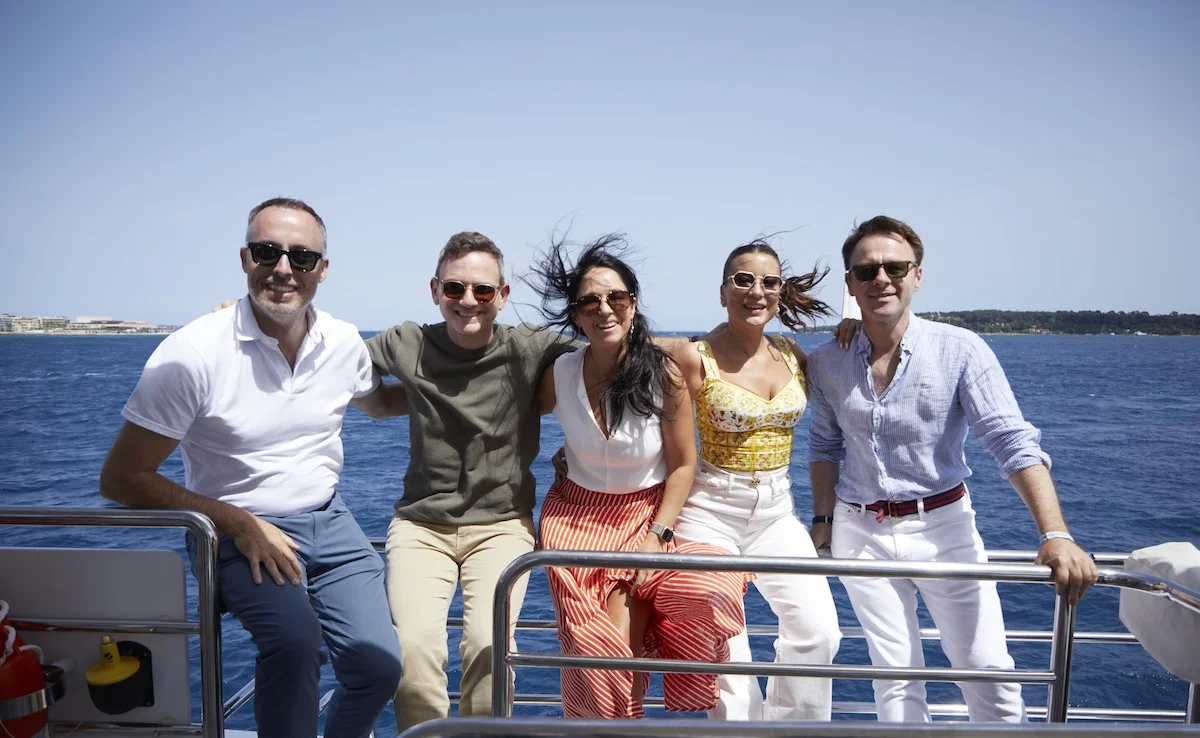 Group of friends enjoying a boat ride on a sunny day with ocean and coastline in the background