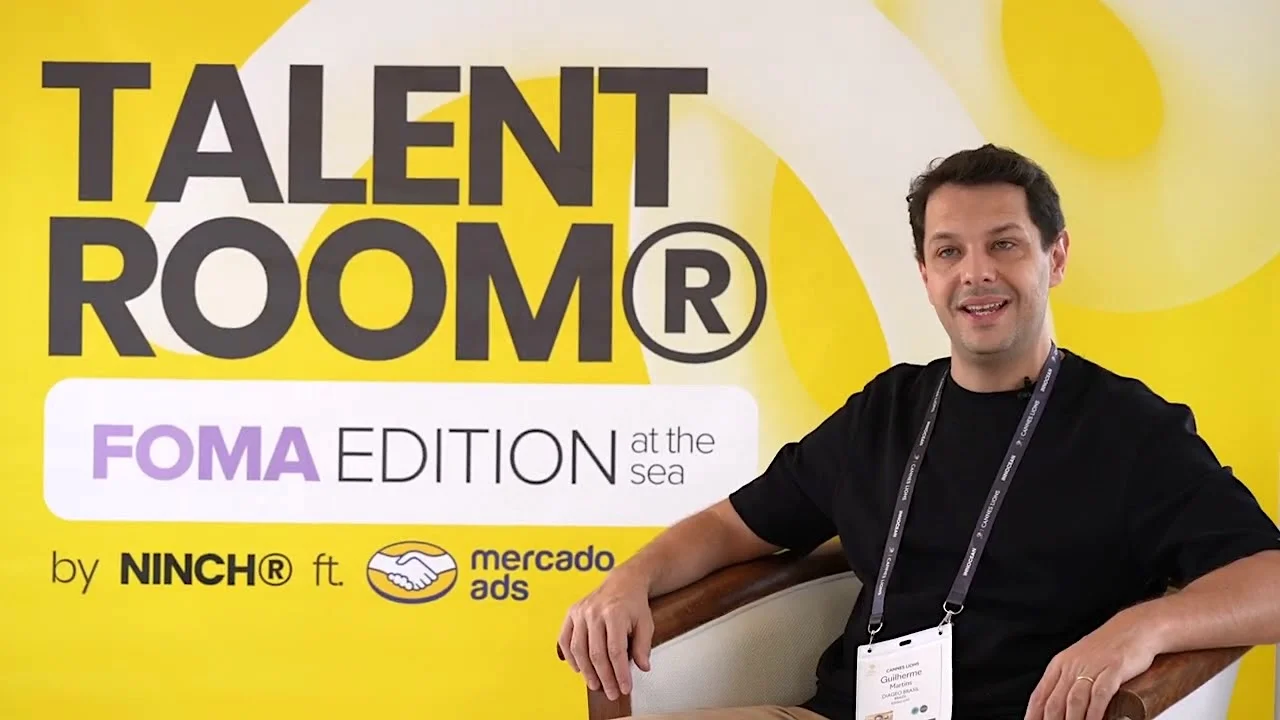 Man sitting in front of Talent Room FOMA Edition event banner by NINCH and Mercado Ads.