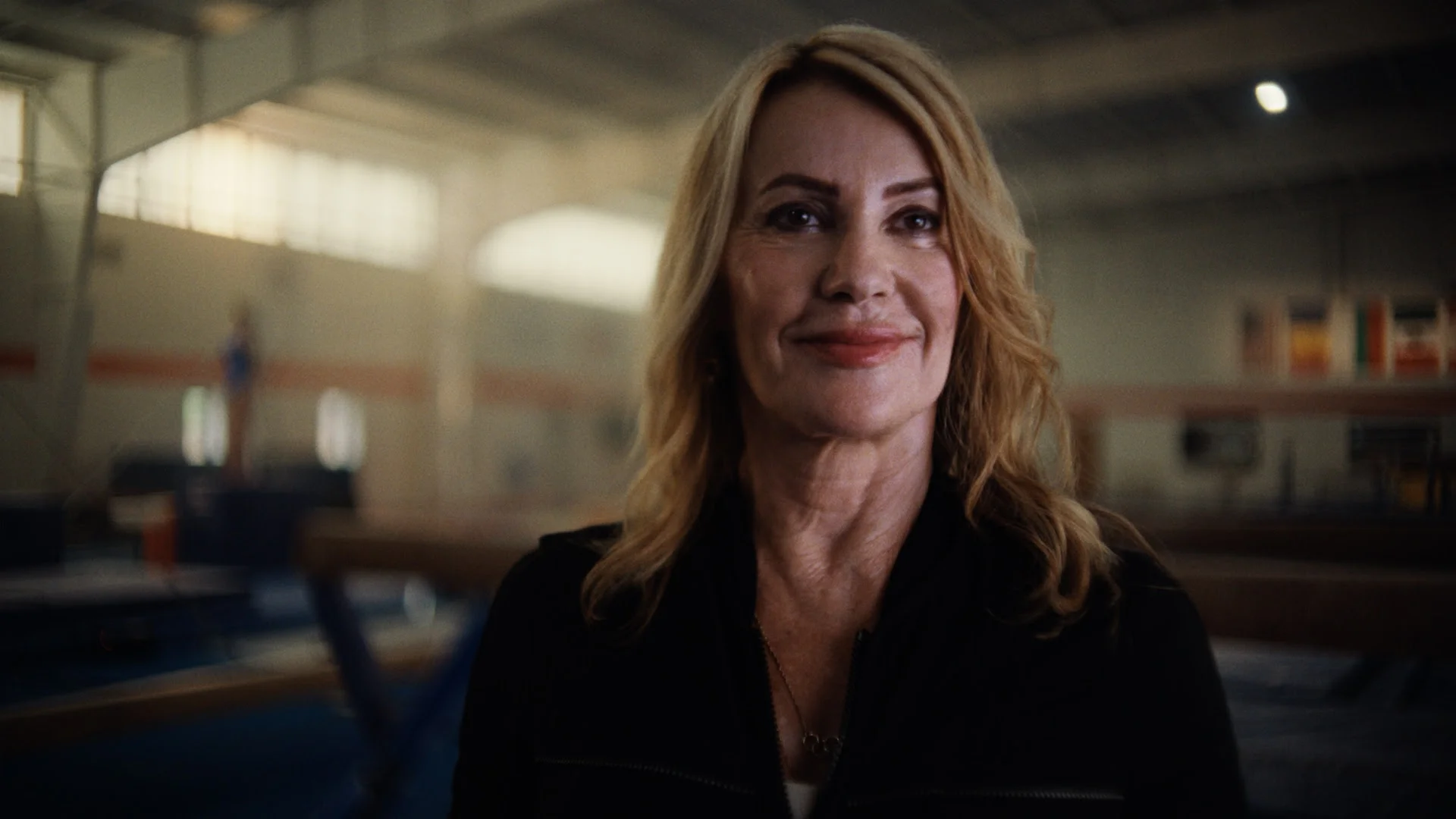 Smiling woman with blonde hair in a gymnasium background