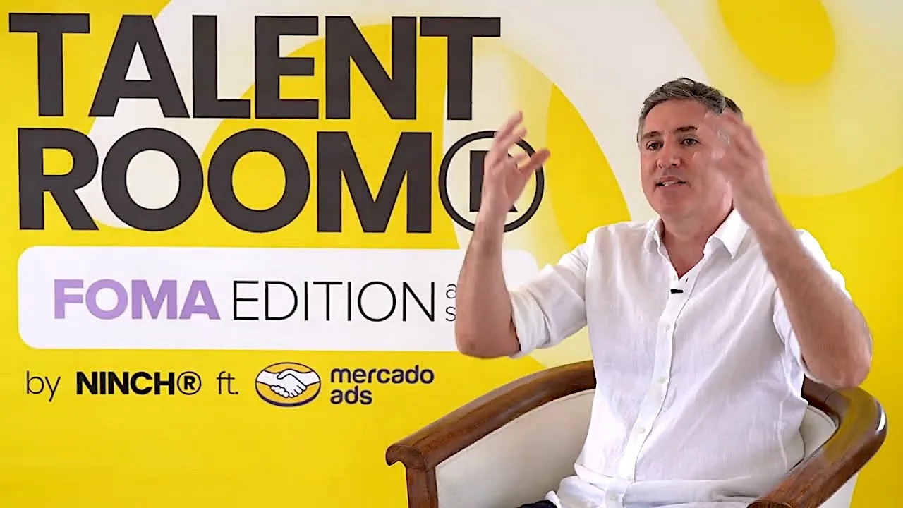 Man speaking at Talent Room FOMA Edition event by Ninch and Mercado Ads, yellow background.