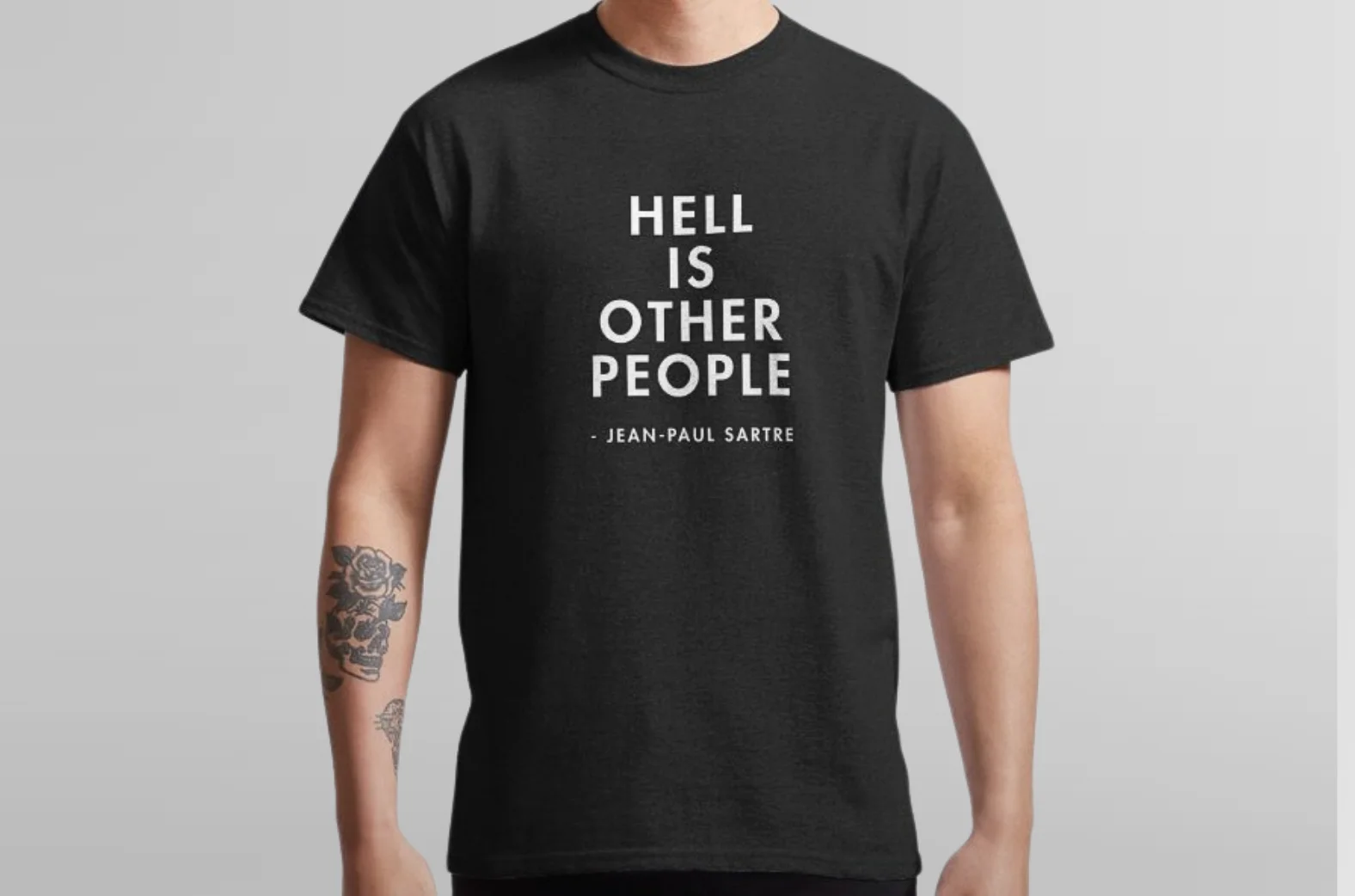 Man wearing black t-shirt with "Hell is Other People" quote by Jean-Paul Sartre, visible tattoo on left arm.