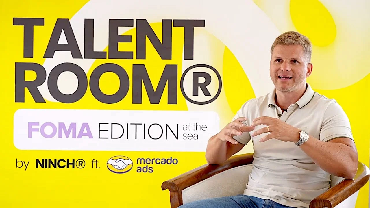 Man speaking during Talent Room FOMA Edition at the Sea event by Ninch and Mercado Ads, yellow background.