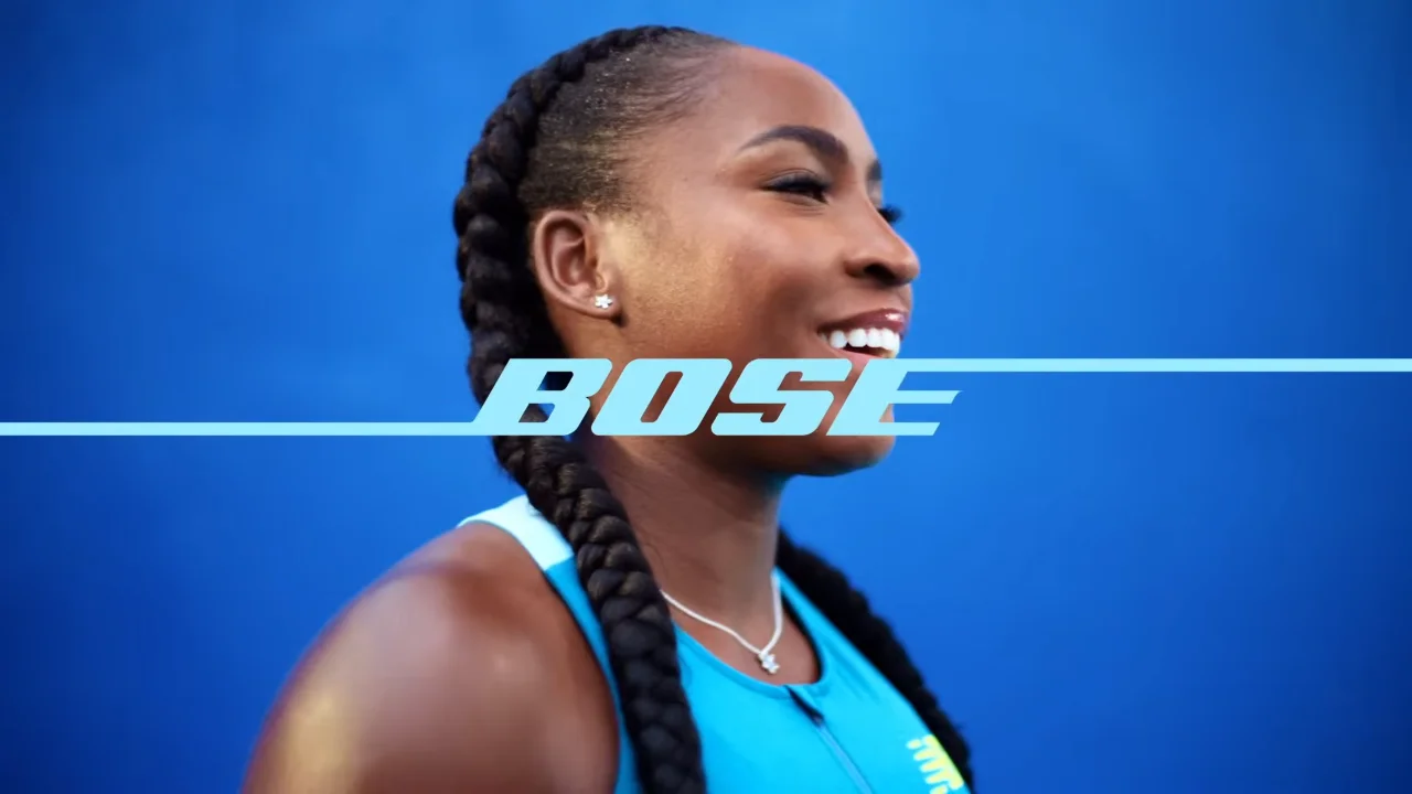 Smiling athlete with braided hair wearing a blue sports outfit, Bose logo overlay, blue background.