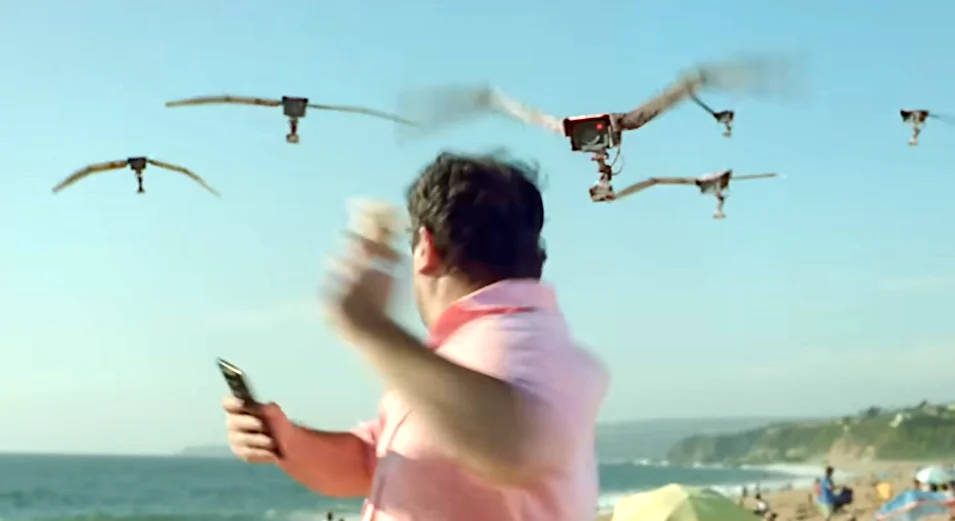 Man on beach reacting to flying drones in the sky.