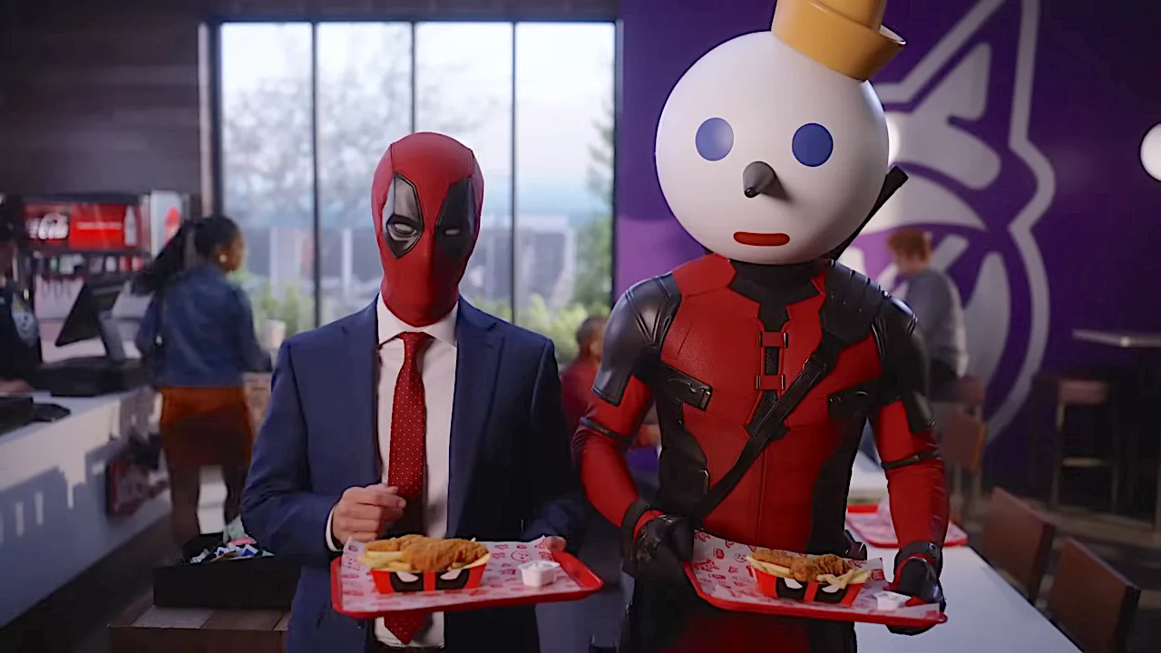 Two people in costumes holding food trays in a fast-food restaurant.