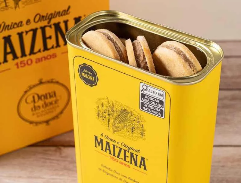 Tin of Maizena cookies featuring a bright yellow design, showcasing the brand's 150-year anniversary, with cookies partially visible inside.