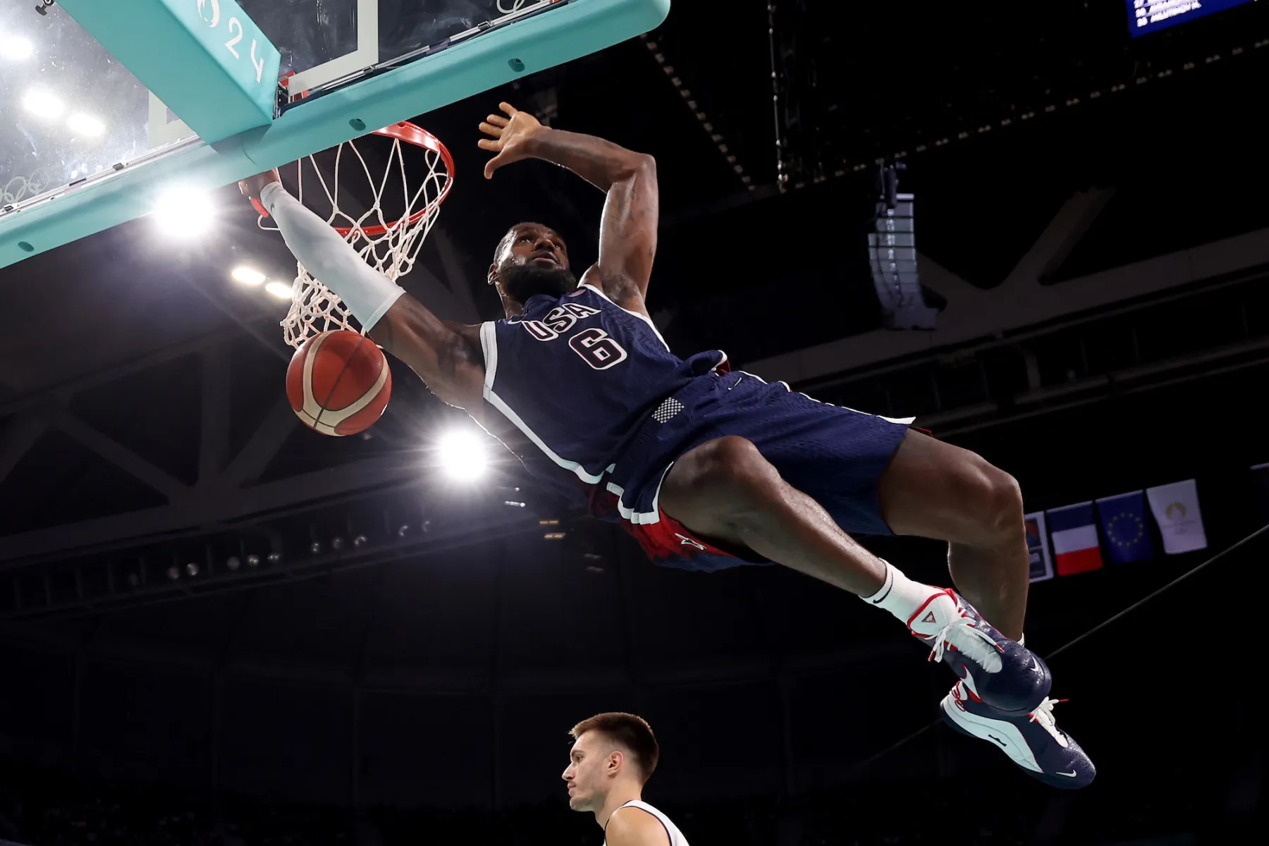 LeBron James performing a powerful dunk during a basketball game, showcasing athleticism and skill. The image captures the intensity of the moment with dramatic lighting and a focused expression.