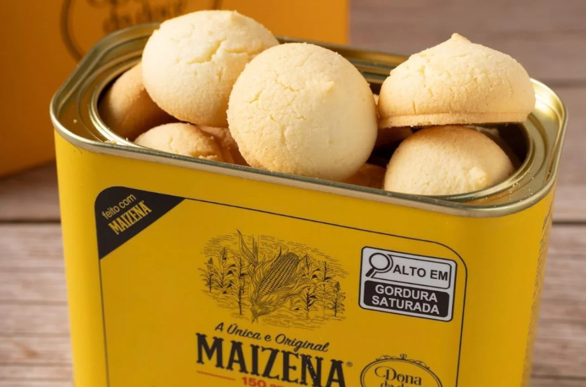 Yellow tin of Maizena cookies filled with round, golden-brown treats, showcasing the product's branding and nutritional information on the packaging.