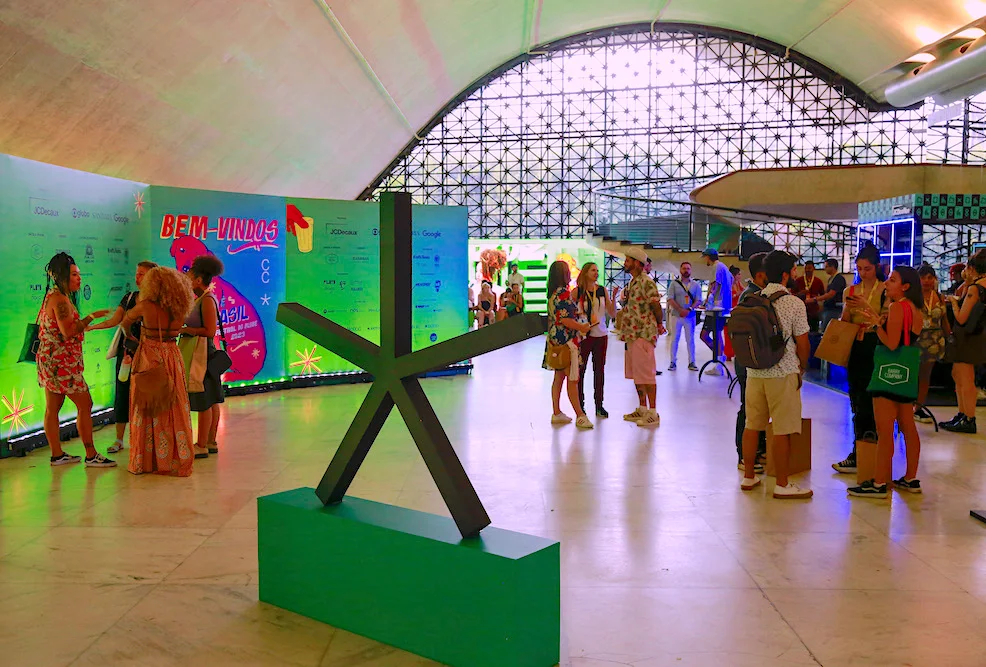 Evento com pessoas e escultura em um saguão moderno.