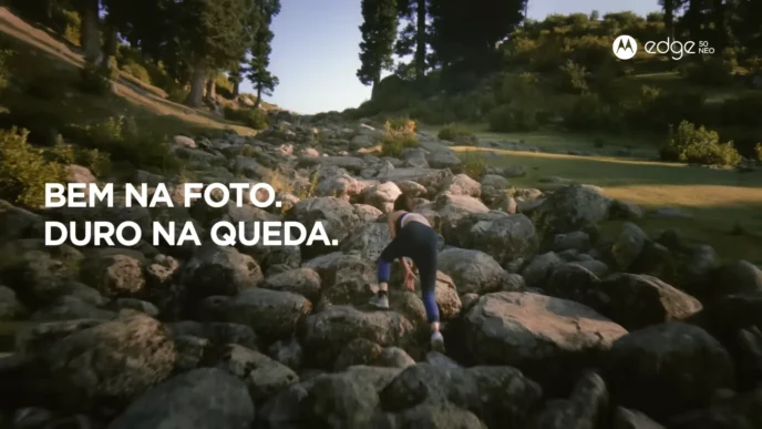 Pessoa escalando pedras em cenário natural com árvores.