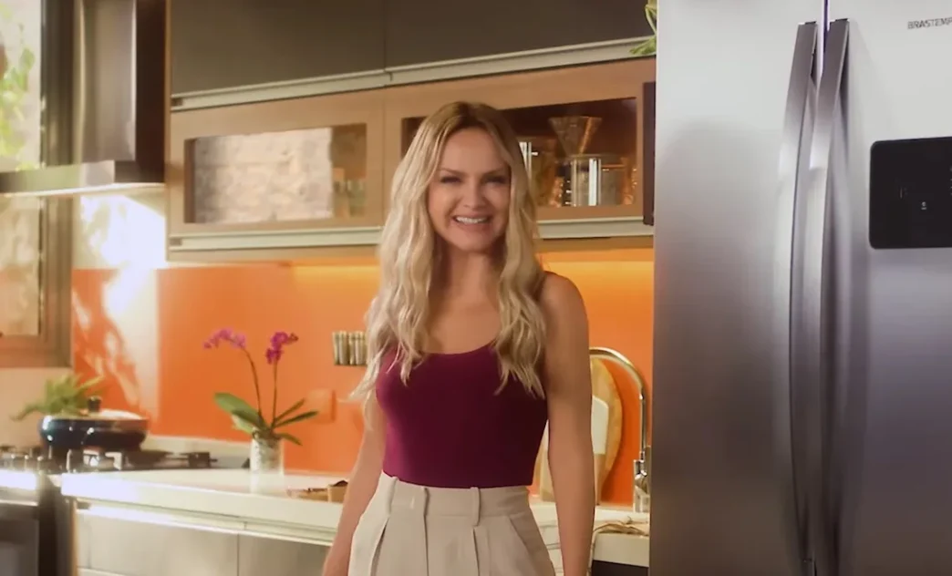 Mulher sorrindo em cozinha moderna com geladeira.