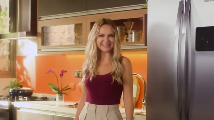 Mulher sorrindo em cozinha moderna com geladeira.