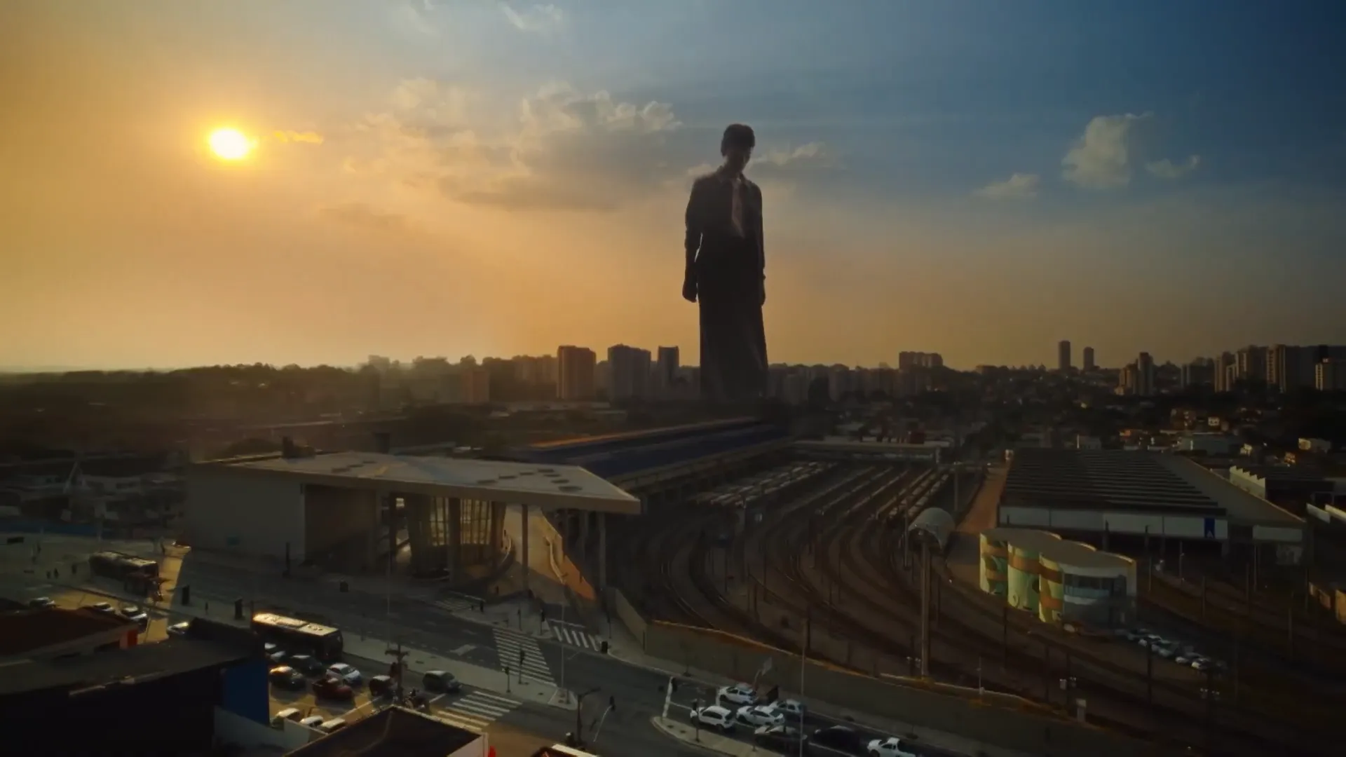 Estação ferroviária ao entardecer com silhueta gigante.