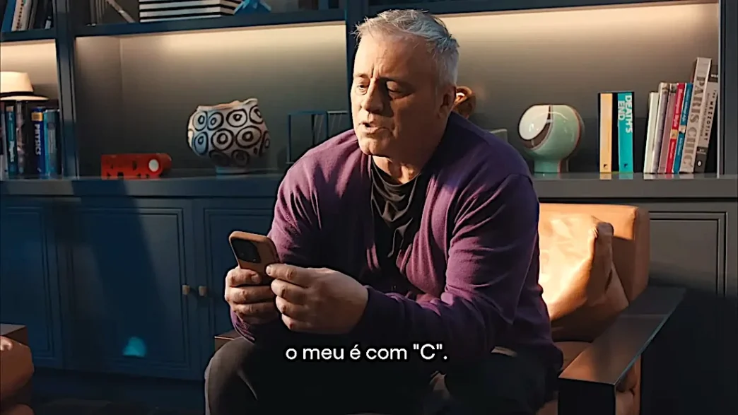 Homem sentado usando smartphone em uma sala aconchegante.