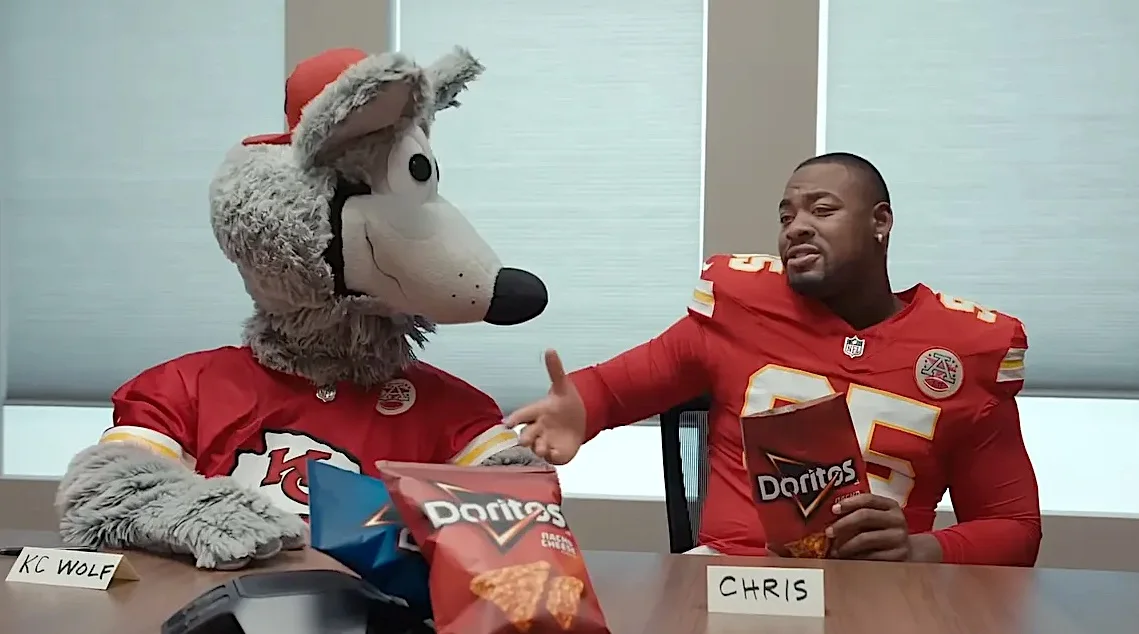 Mascote do Chiefs e jogador comendo Doritos.