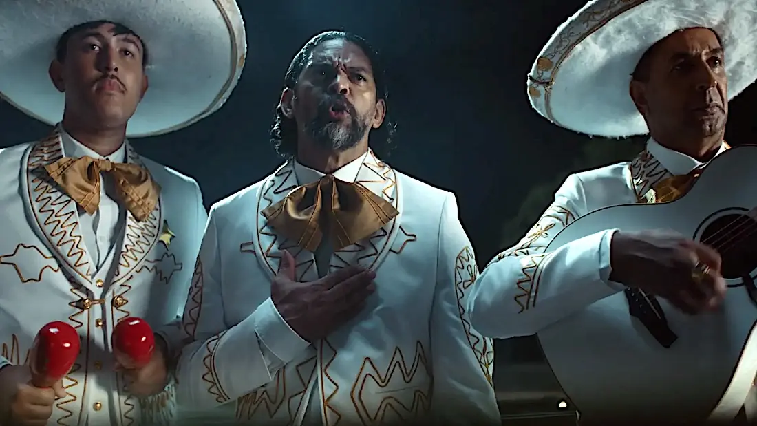 Trio mariachi cantando em trajes tradicionais mexicanos.