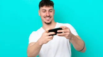 Homem sorrindo jogando no celular, fundo azul