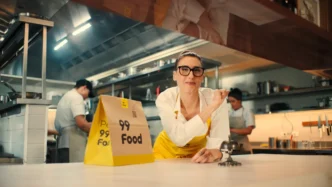 Cozinha com sacola de entrega amarela e equipe ao fundo.