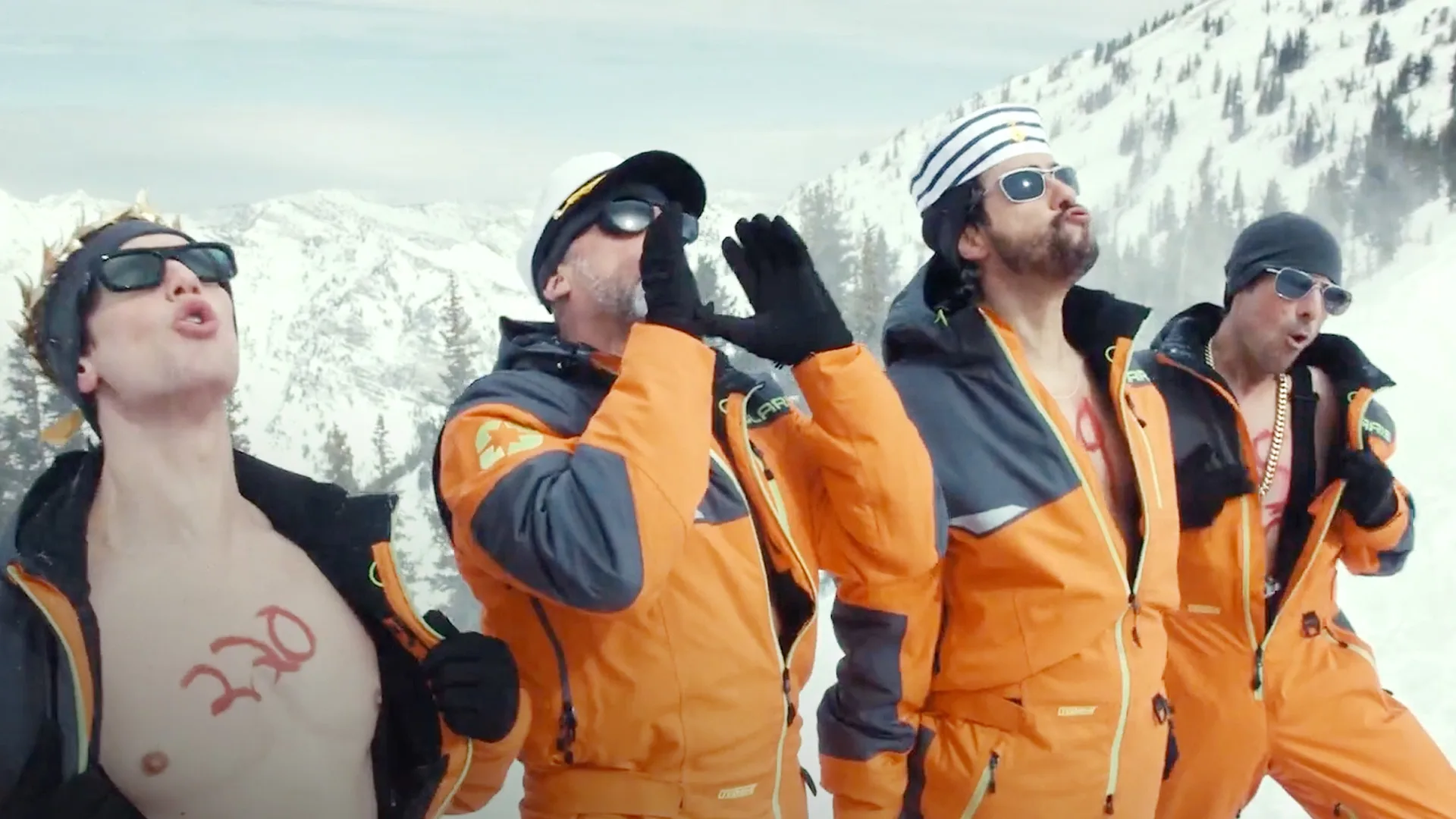 Homens de macacão laranja na neve gritando animados.