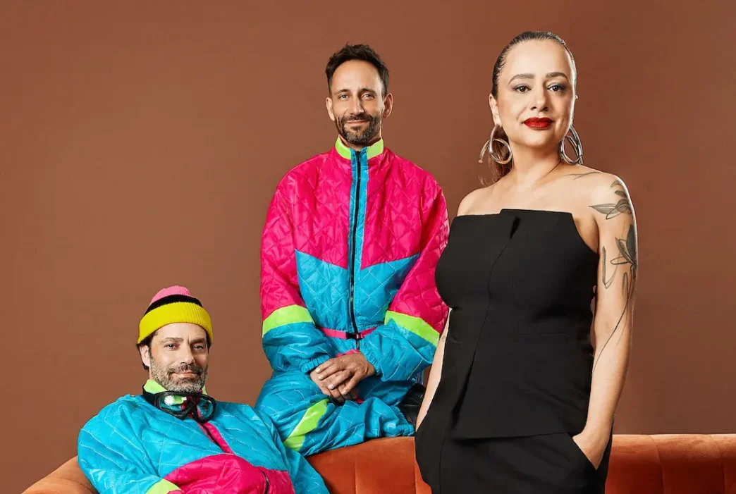 Três pessoas vestidas em roupas coloridas.