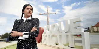 Mulher em traje formal perto de estrutura gigante.