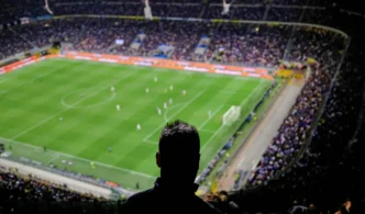 Torcida assiste a jogo de futebol no estádio lotado.