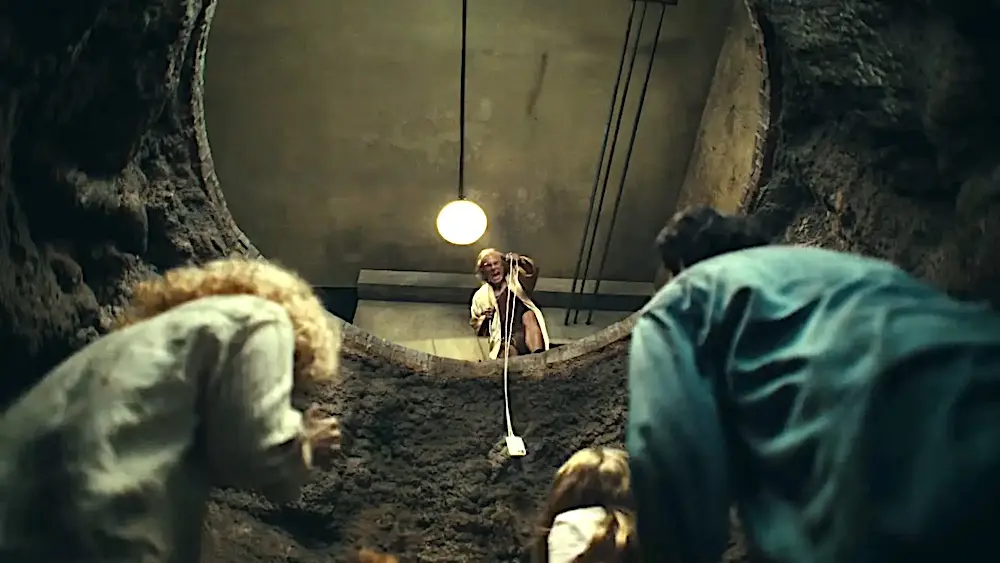 Pessoas olham de dentro de um buraco subterrâneo.