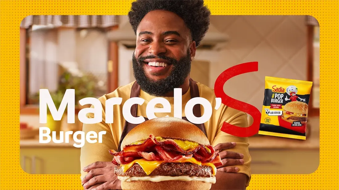 Homem sorrindo com hambúrguer e pacote de Sadia.