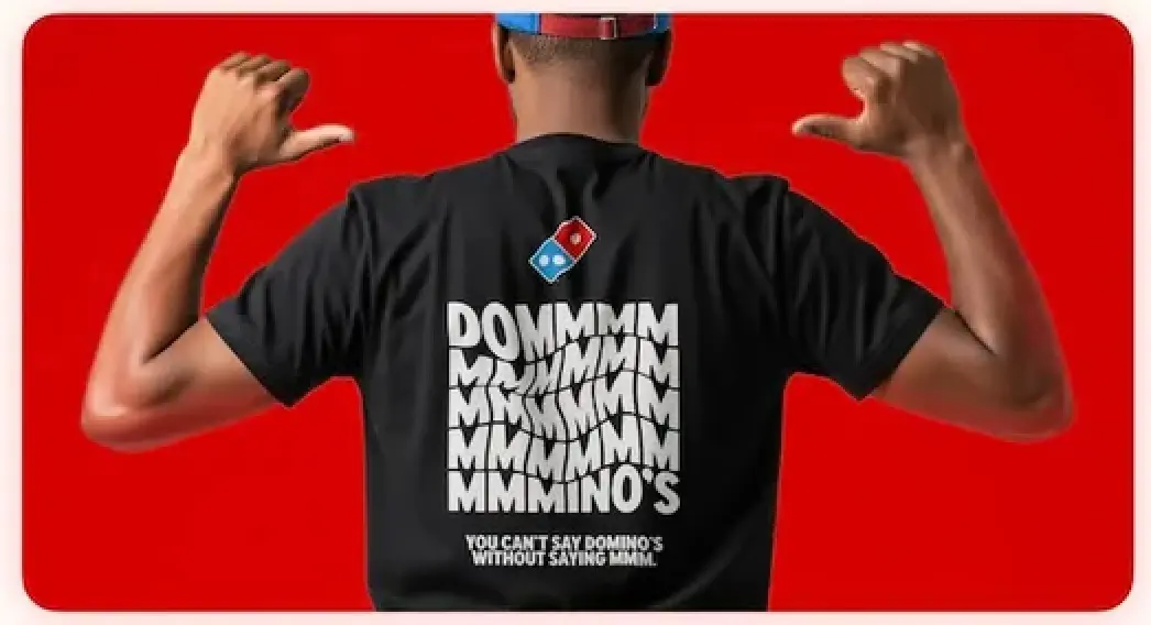 Pessoa com camiseta Domino's, fundo vermelho.
