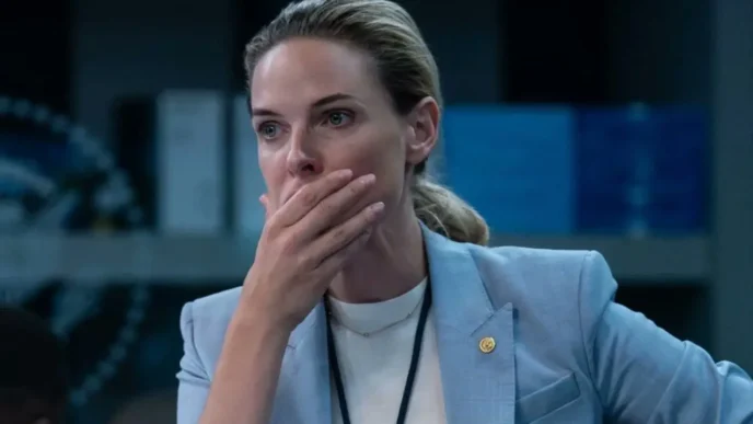 Pessoa surpresa, mão cobrindo a boca, roupa formal.