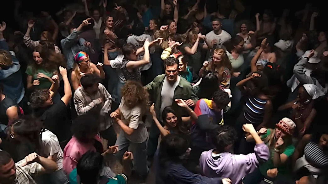 Pessoas dançando animadamente em festa movimentada.