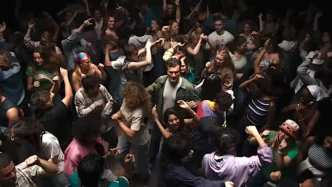 Pessoas dançando animadamente em festa movimentada.