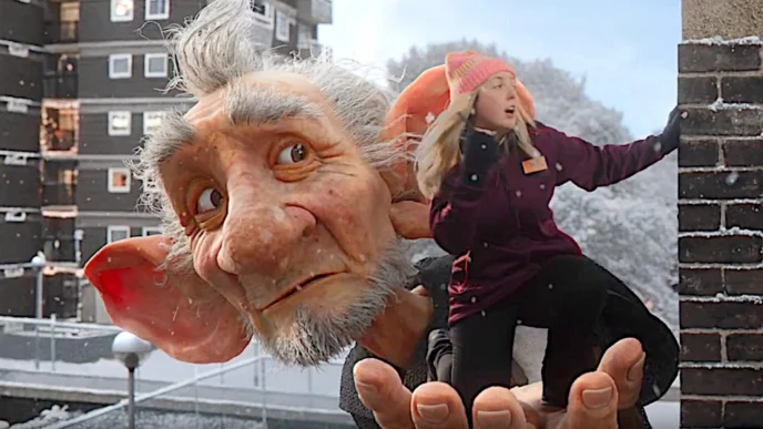 Gigante segura pessoa em ambiente urbano nevado.