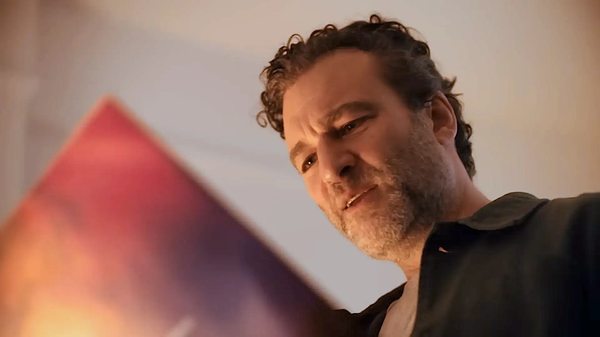 Homem observando objeto obscuro com atenção.